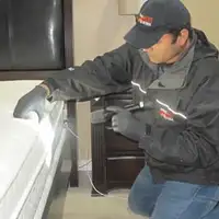 Bed bug inspection technician checking a mattress and bed frame for signs of infestation in Little Rock, AR