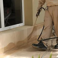 General pest control technician spraying exterior perimeter around a home in Little Rock, AR