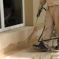 General pest control technician spraying exterior perimeter around a home in Little Rock, AR