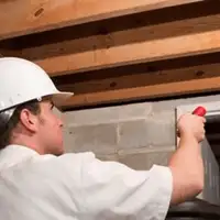 Termite inspection technician checking a basement wall and framing for termite activity in Little Rock, AR